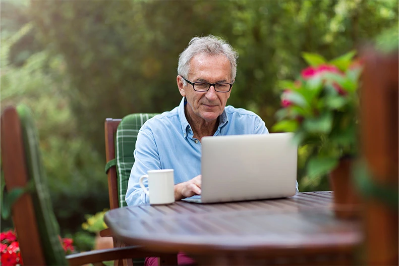 Man working in garden on laptop