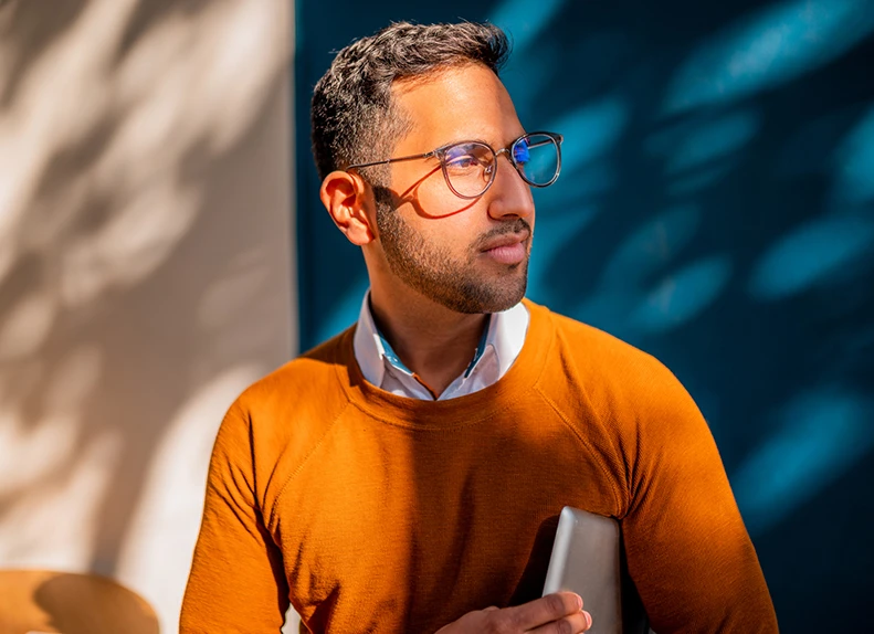 Man with orange jumper holding a tablet