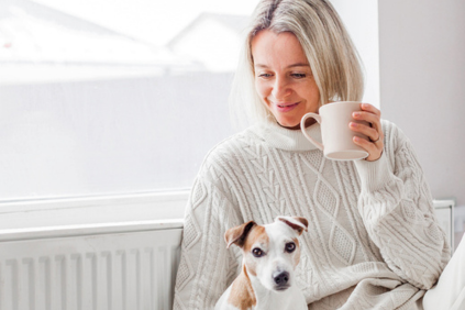 Woman on couch with dog and cup of coffee