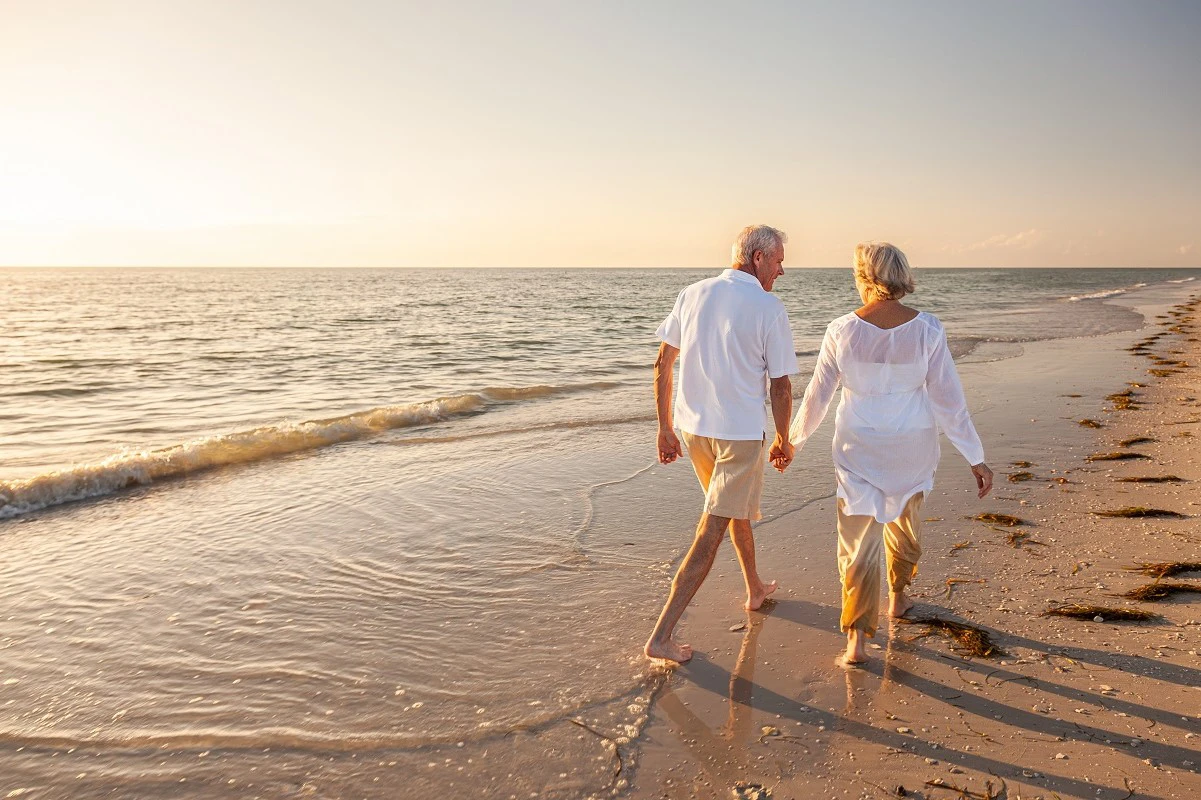 Retired Couple Walking On Beach